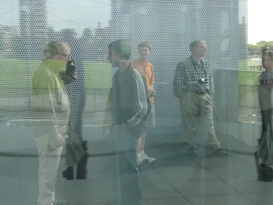 Reflections of six people gathering in a glass yin/yang sculpture.