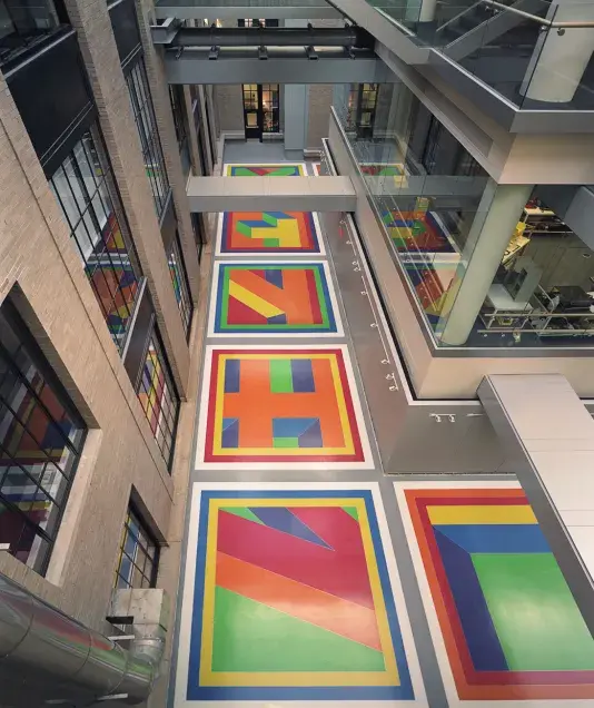 Sol Lewitt's colorful Terrazzo floor including red, green, orange, purple, and yellow tiles inside a building with high ceilings.