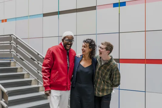 Three Altered Access participants stand next to one another with their arms around each other laughing.